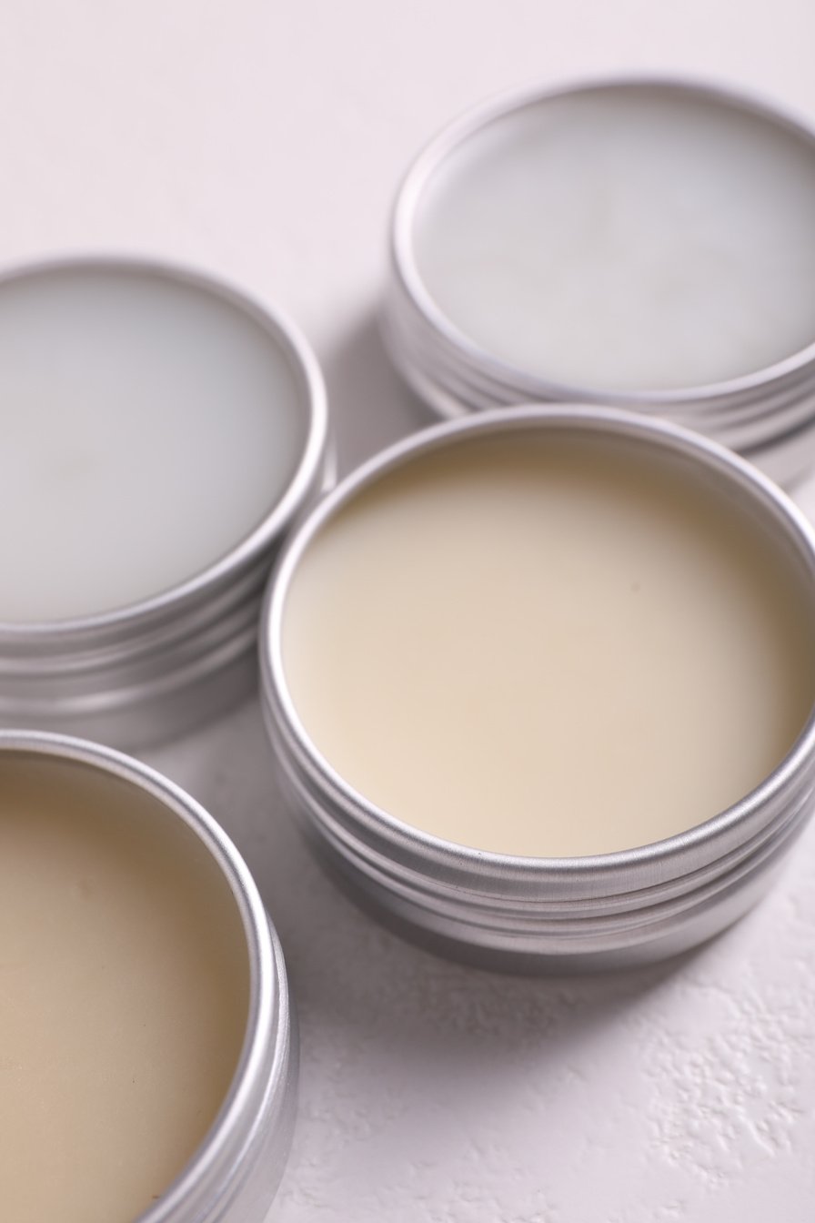 Different Lip Balms on White Table, Closeup
